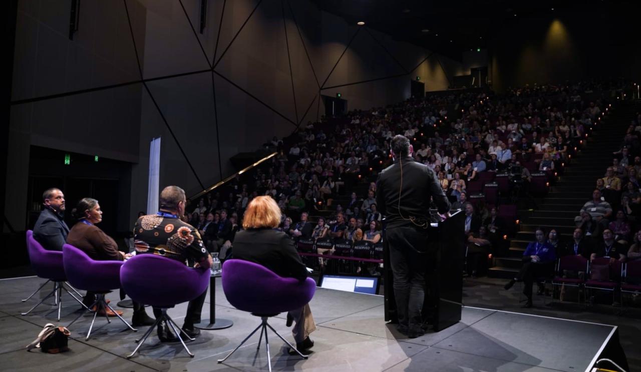 Discussion panel addressing crowd, from a wide view at the back of the stage at Australian Homelessness Conference 2024